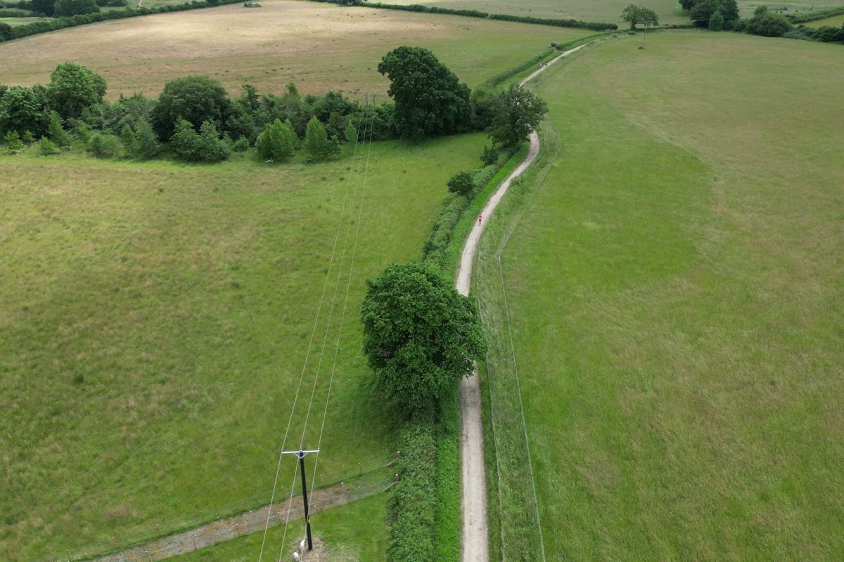 The track snaking along a hedge line through open fields