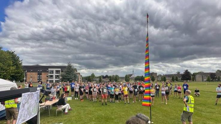 Runners gathered on the field at Harcourt Hill for the race briefing under a big sky, 2025